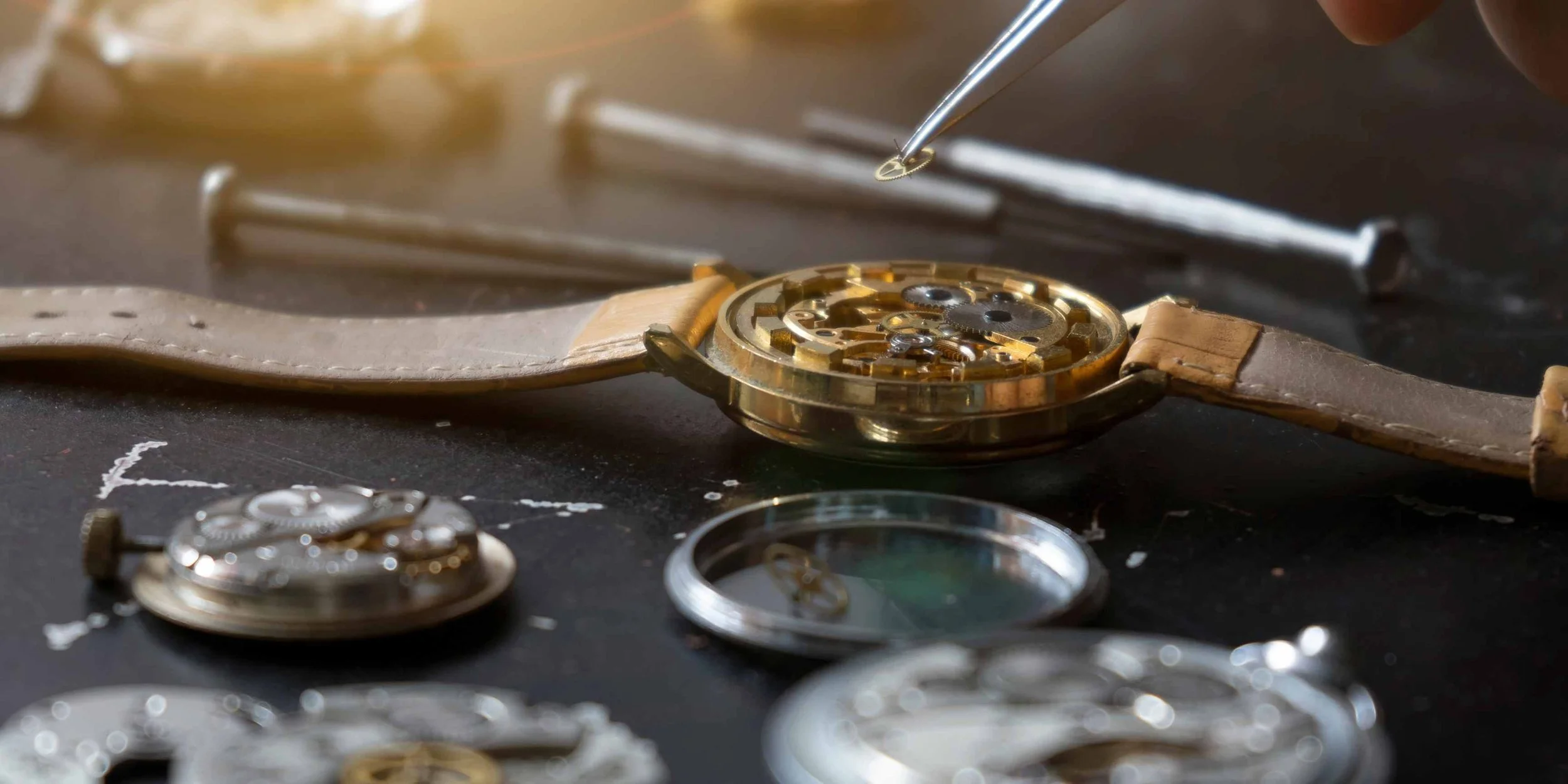 Watchmaker's precision tools arranged beside a mechanical watch movement